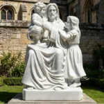Hand-carved white marble statue of Jesus with two children in an outdoor church garden.