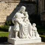 A detailed white marble statue of Jesus with three children, seated outdoors against a stone wall in a serene garden setting.