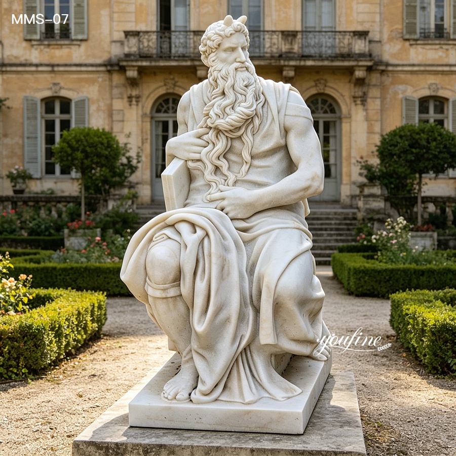Intricately carved marble statue of Moses with a flowing beard, seated in a beautiful garden setting in front of a historic building.