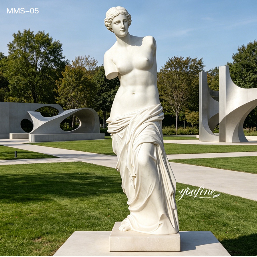 Elegant marble statue of a Venus-style figure with classical drapery displayed in a modern outdoor park with landscaped greenery and abstract sculptures.