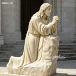 A detailed marble sculpture of Jesus kneeling in prayer, set against a stone architectural background.