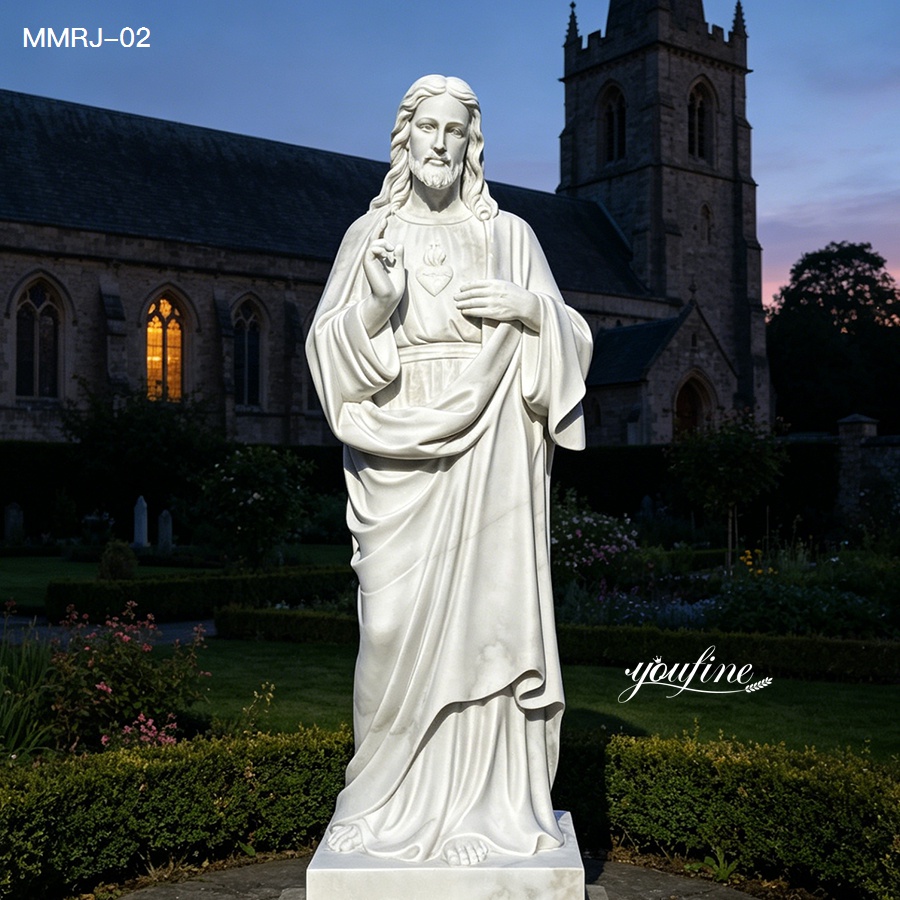 Elegant white marble statue of the Sacred Heart of Jesus, featuring intricate details, placed in a garden with a church at dusk.