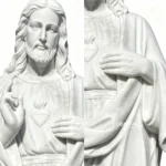 Close-up view of a white marble statue of the Sacred Heart of Jesus, showcasing intricate details on the facial features, hands, and clothing.